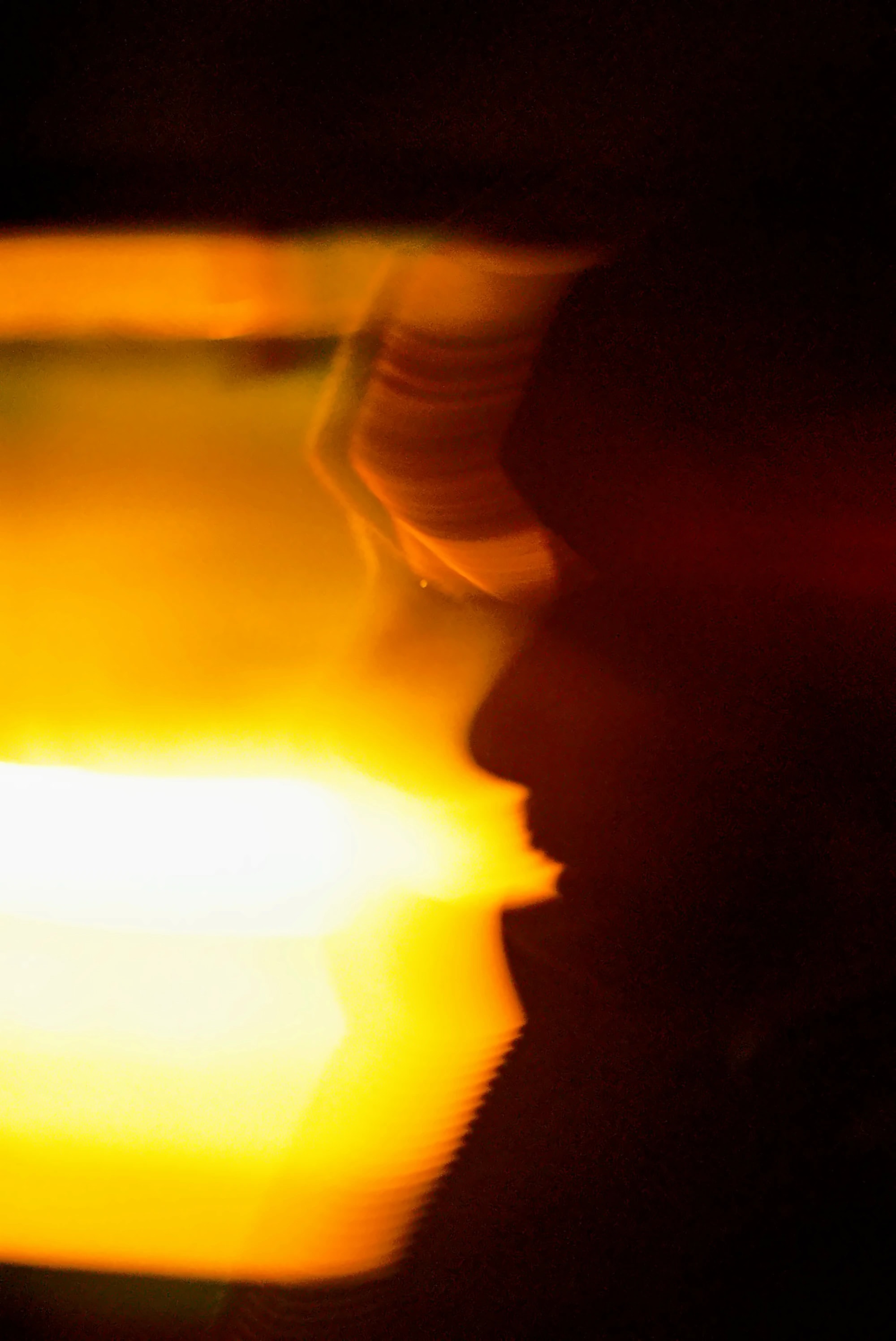 Candlelit profile in silhouette against a burning wash of yellow light, a 35mm film photograph by Grant Parkhurst
