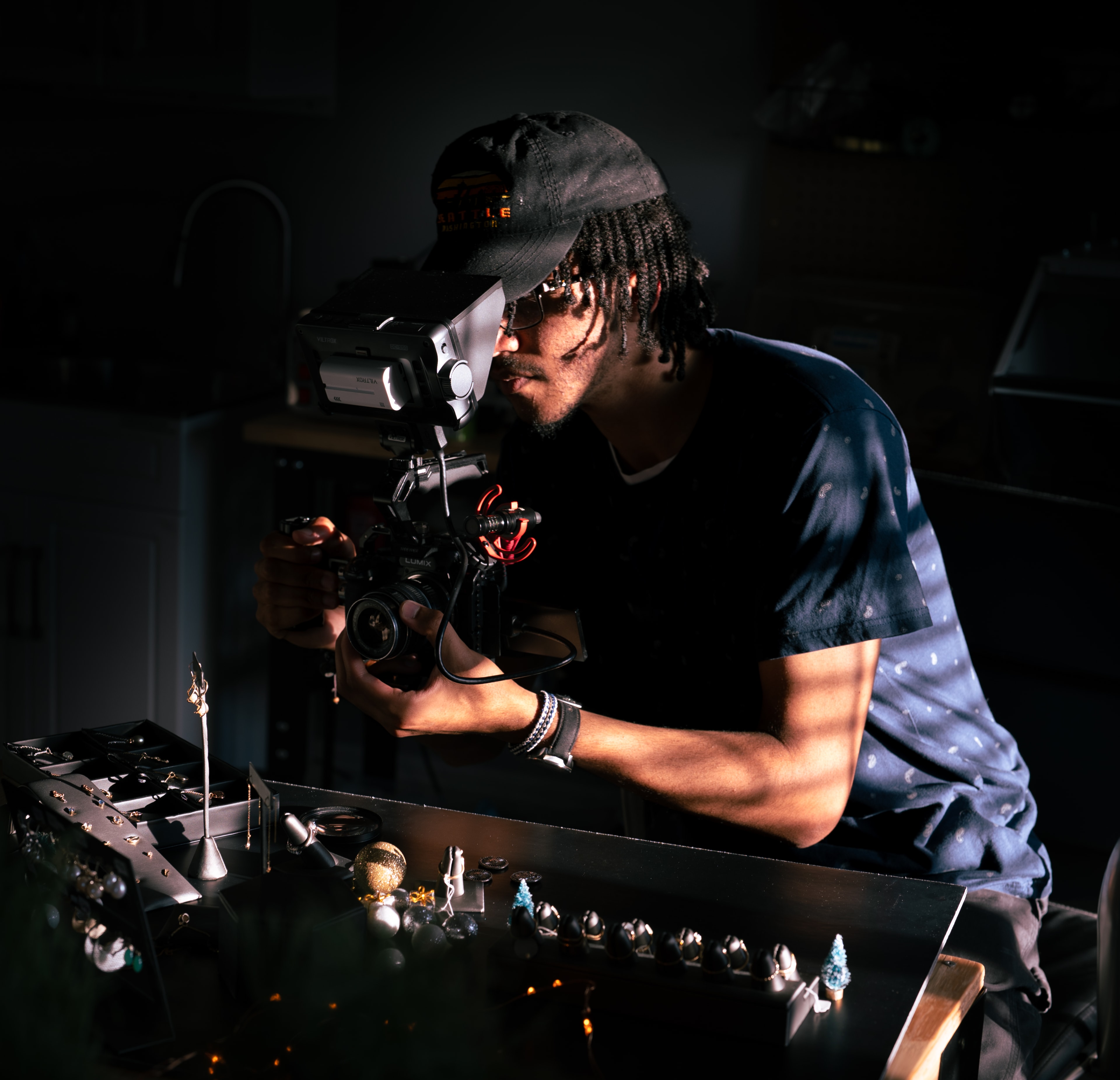 Behind the scenes on a jewelry product shoot, videographer working over a lit table